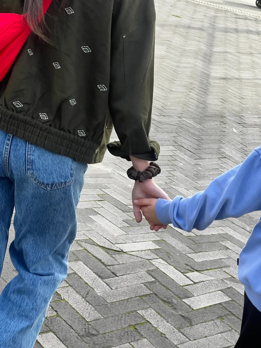 Two people holding hands outdoors, one wearing a brown Kova Silk scrunchie on the wrist